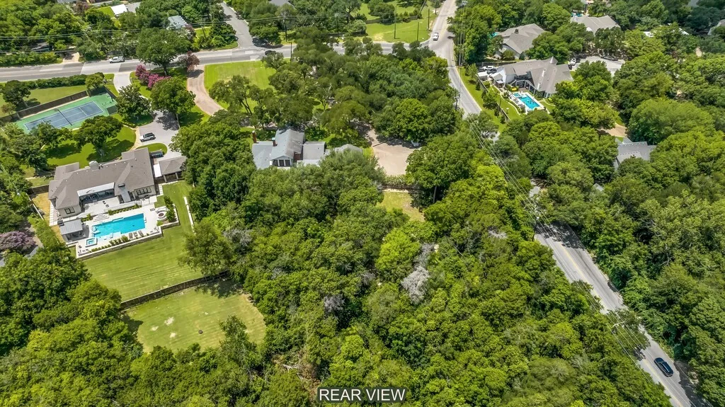Expansive, tree-lined property featuring a large residence with a private swimming pool, surrounding patio, and a vast lawn area