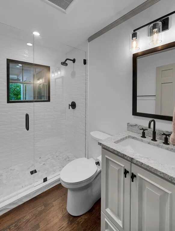 Full bathroom featuring a walk-in shower with clear glass enclosure and a black-framed window