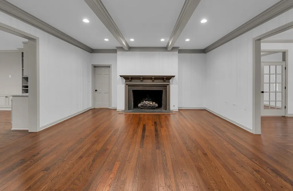 Spacious interior featuring wood-finish flooring, a central fireplace with an ornate mantel, recessed lighting, and crown molding