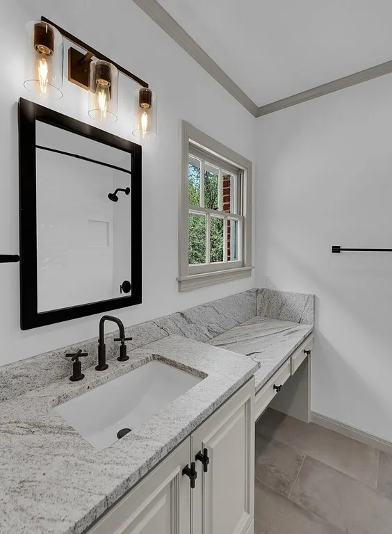 Expansive vanity featuring a built-in rectangular sink, light granite countertop, and matte black faucet