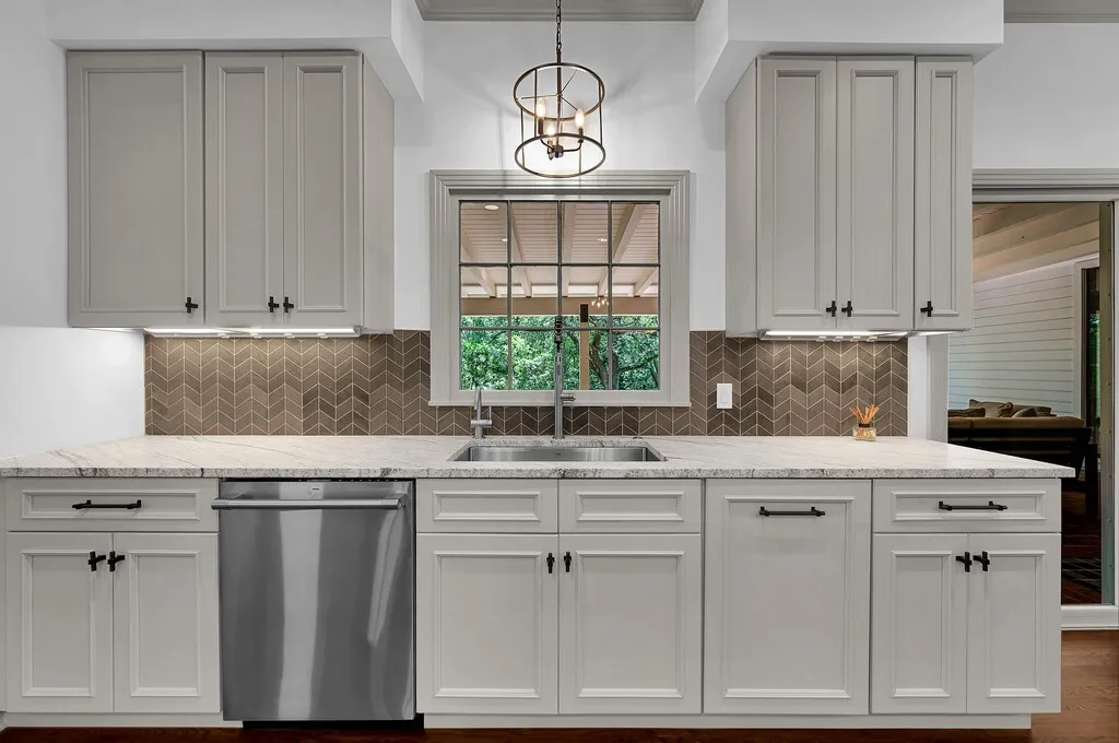 Kitchen space featuring light-colored cabinetry with dark hardware, a stainless steel sink, and a stainless steel dishwasher
