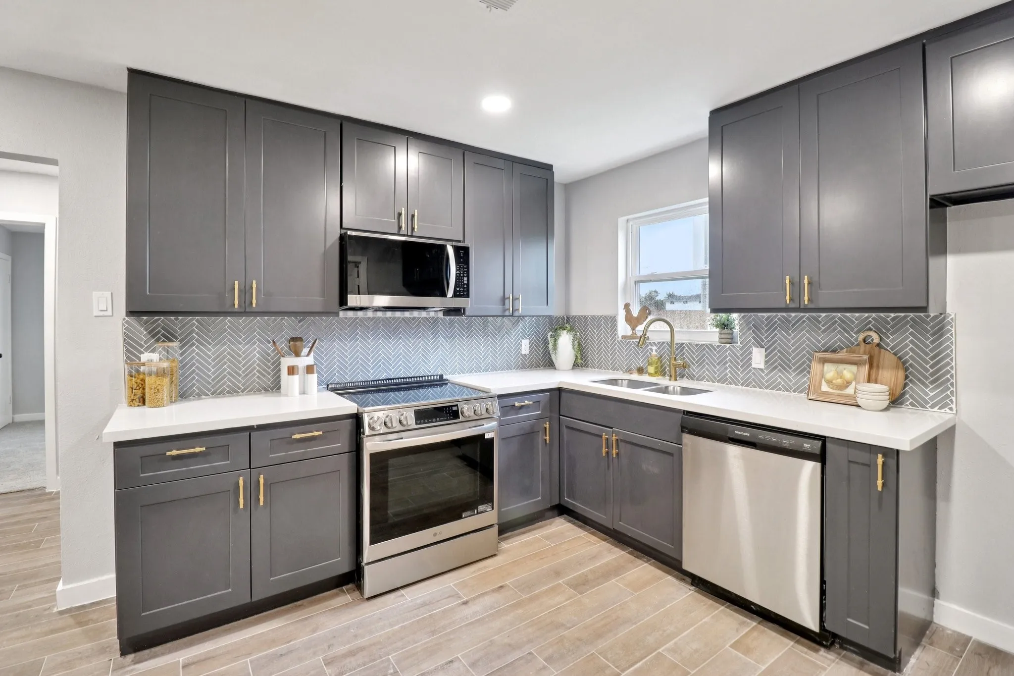 Modern kitchen featuring grey shaker-style cabinetry, white countertops, and a grey herringbone tile backsplash