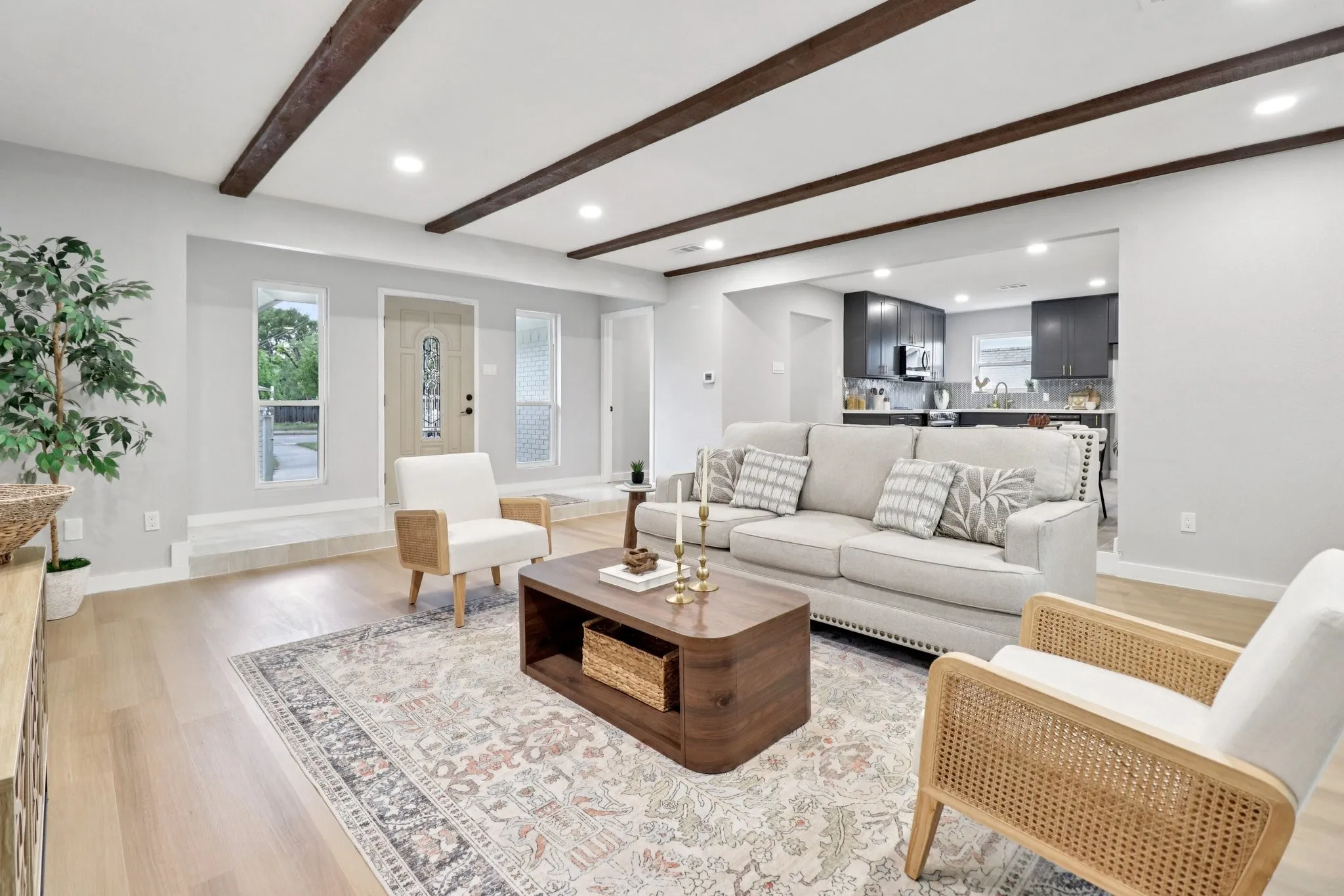 Open-concept living area featuring exposed wood ceiling beams, light wood-finish flooring, and recessed lighting