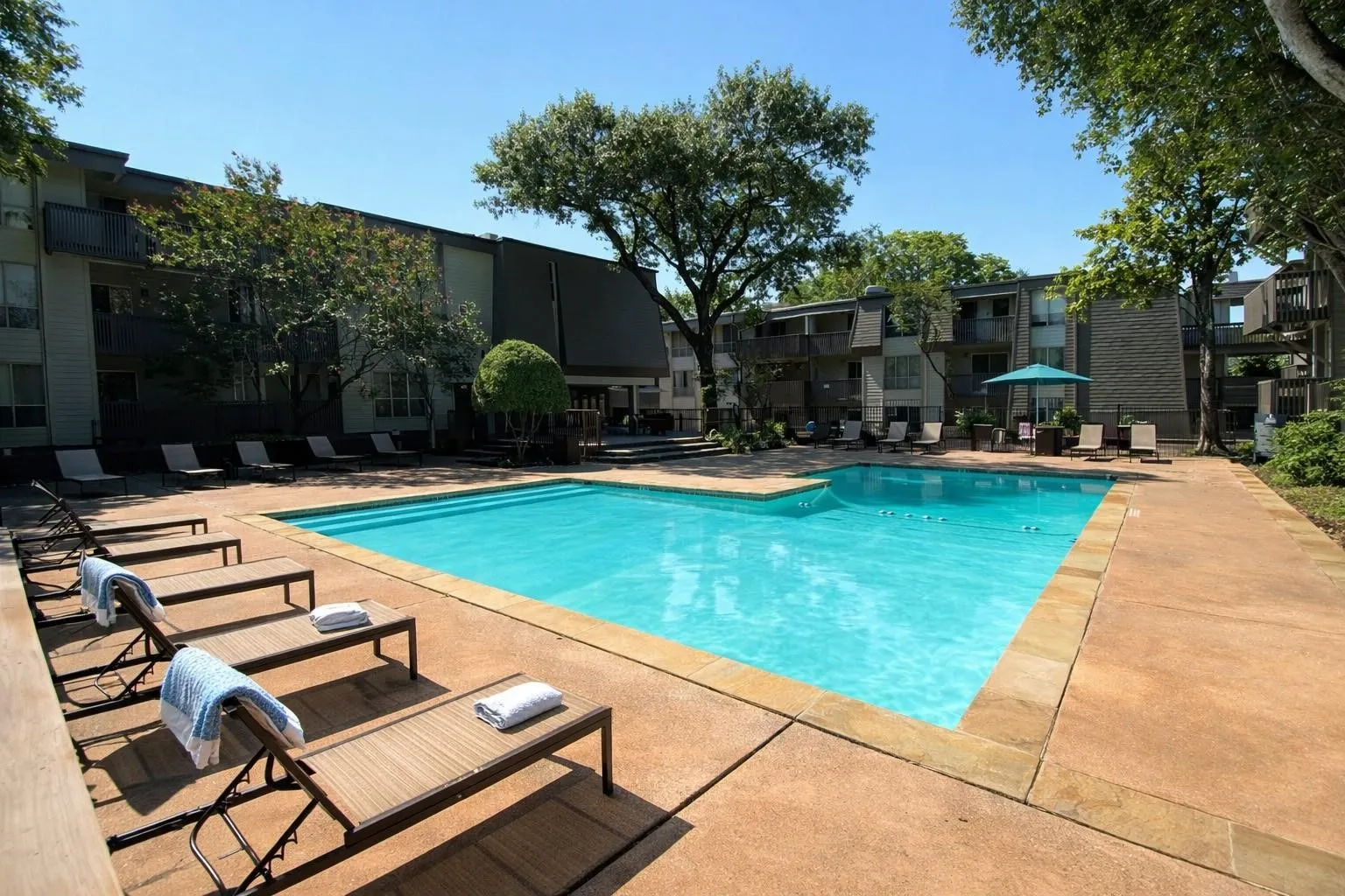 Expansive outdoor swimming pool featuring a perimeter of concrete decking with stone coping