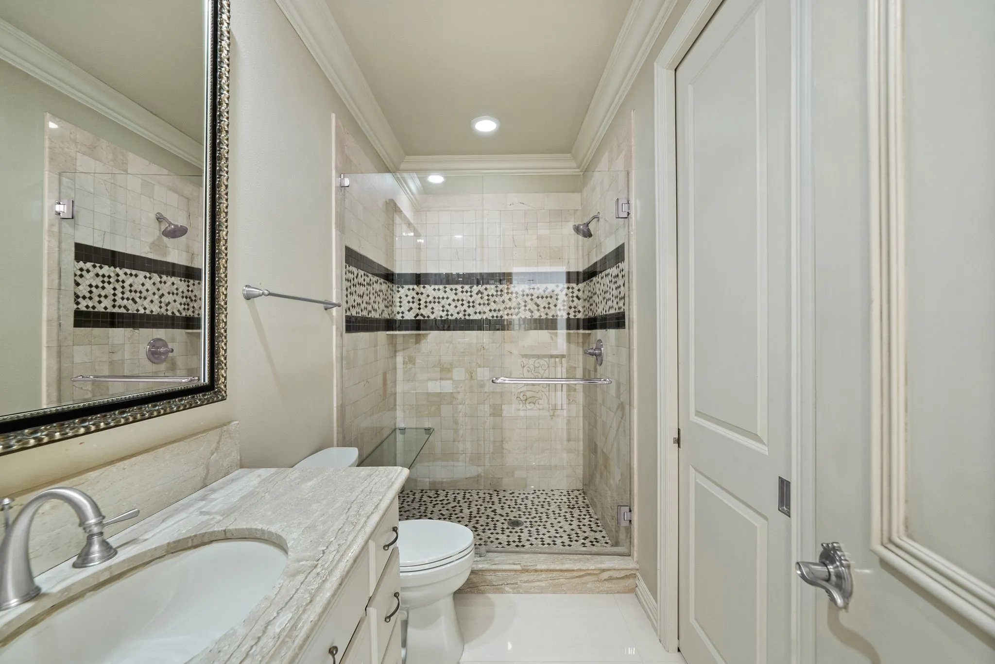 Bathroom featuring a walk-in shower with glass enclosure, mosaic tile accents, and pebble floor