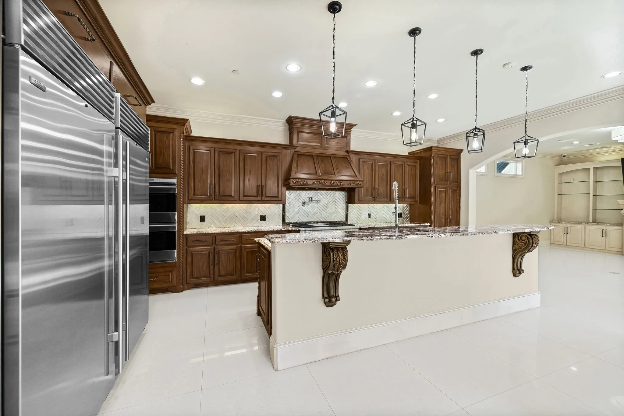 Kitchen featuring an oversized island with a stone countertop, dark wood cabinetry, stainless steel appliances, and four pendant light fixtures