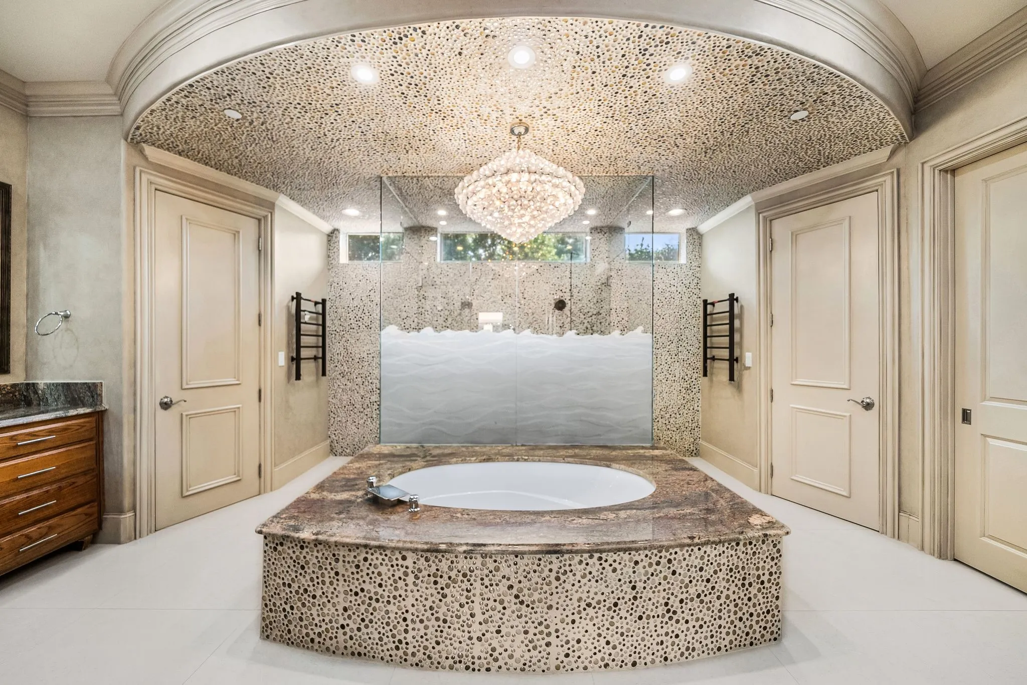 Freestanding oval soaking tub with a mosaic-tiled surround and stone countertop