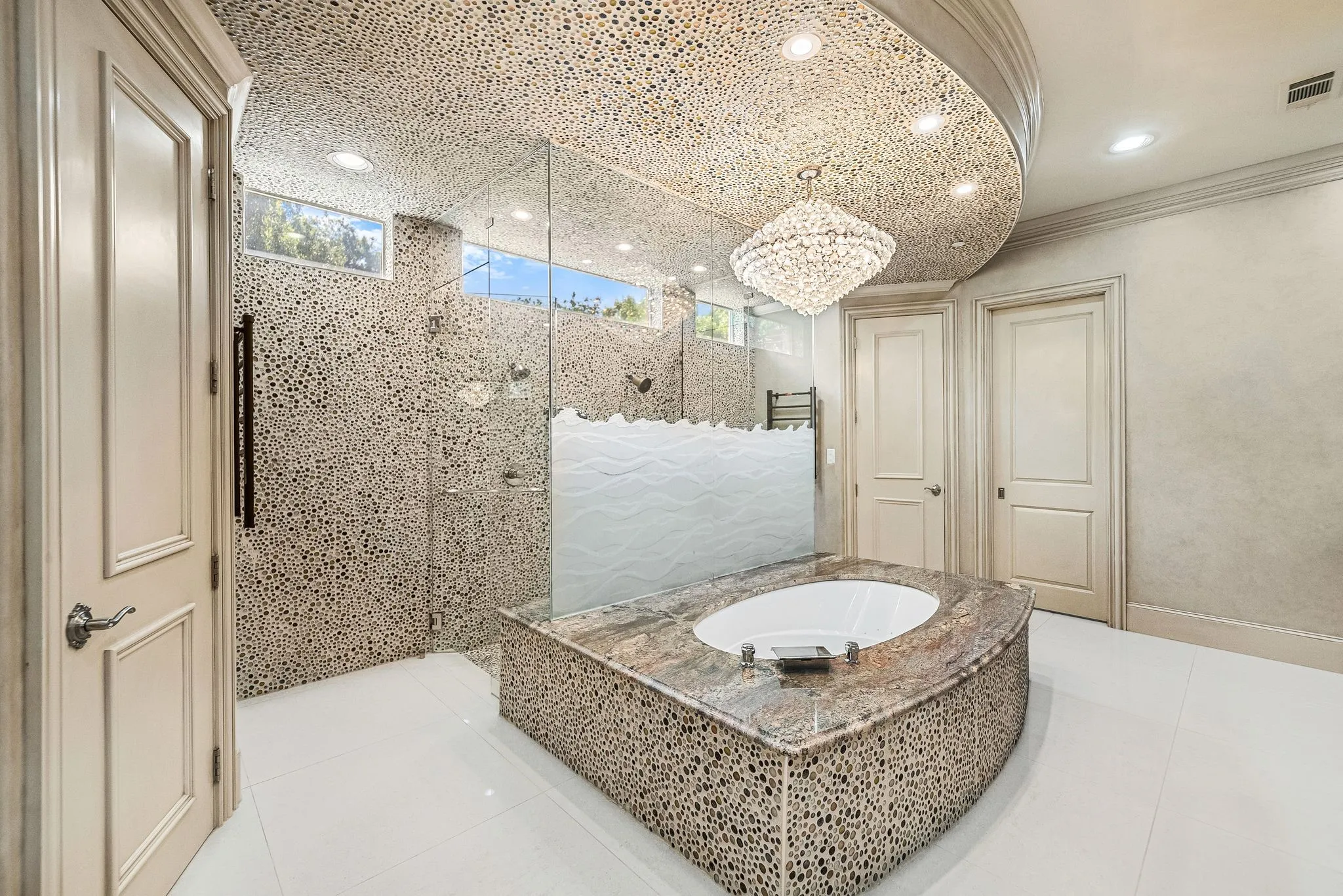 Soaking tub with a natural stone surround and a crystal chandelier