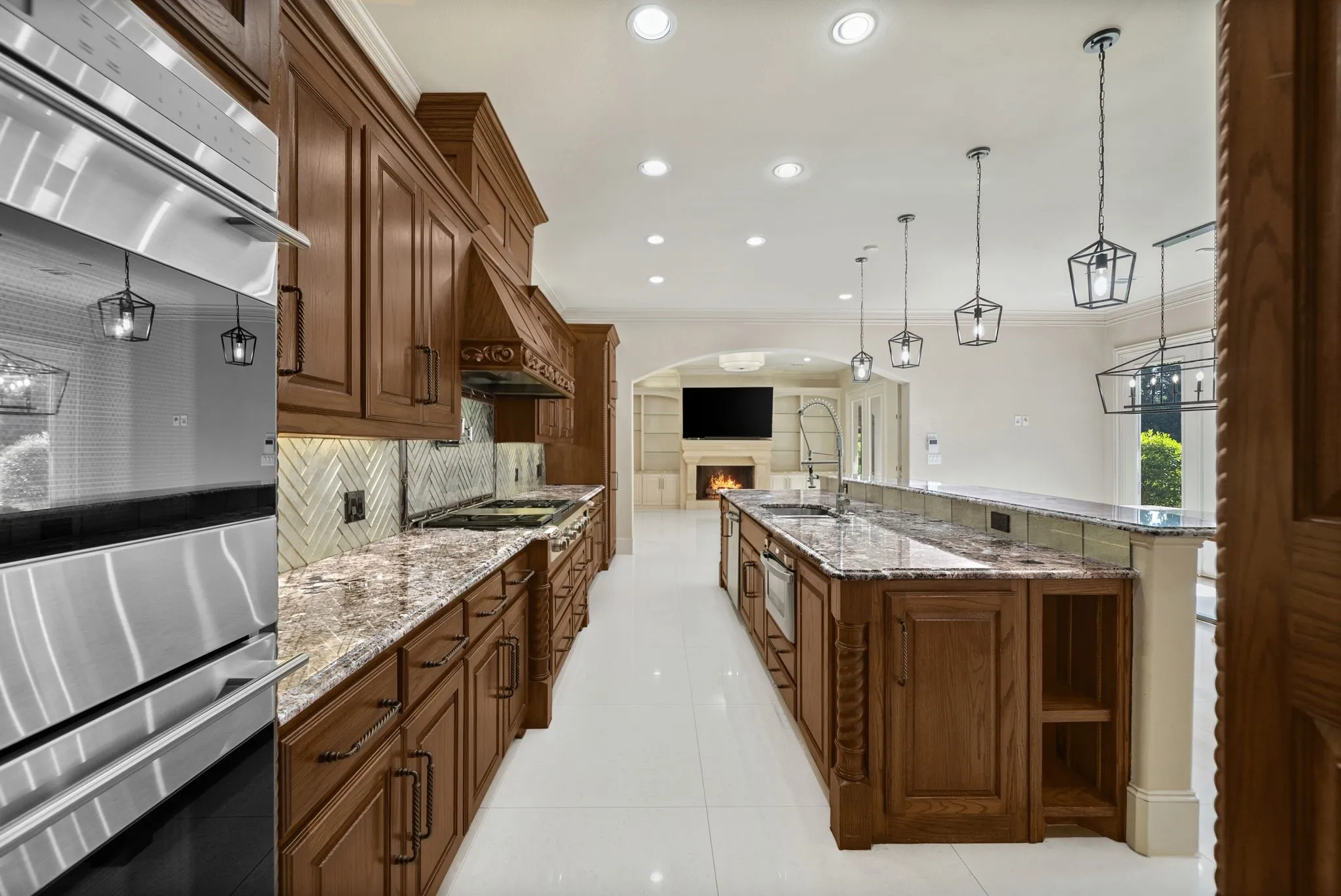 Gourmet kitchen featuring extensive wood cabinetry, stainless steel appliances, granite countertops, and a herringbone tile backsplash
