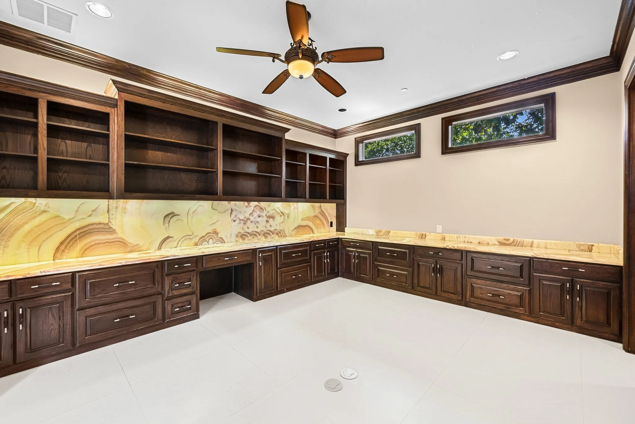 Built-in dark wood cabinetry with integrated shelving, a desk area, and a striking stone backsplash
