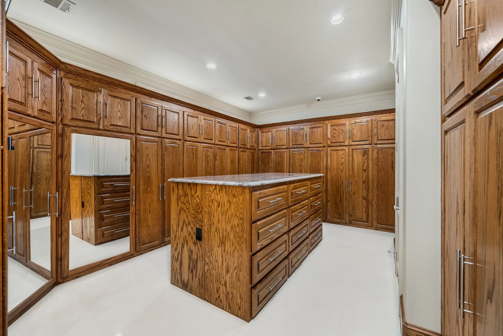 Custom cabinetry storage system featuring a central island with integrated drawers, granite countertop, and floor-to-ceiling wooden cabinets