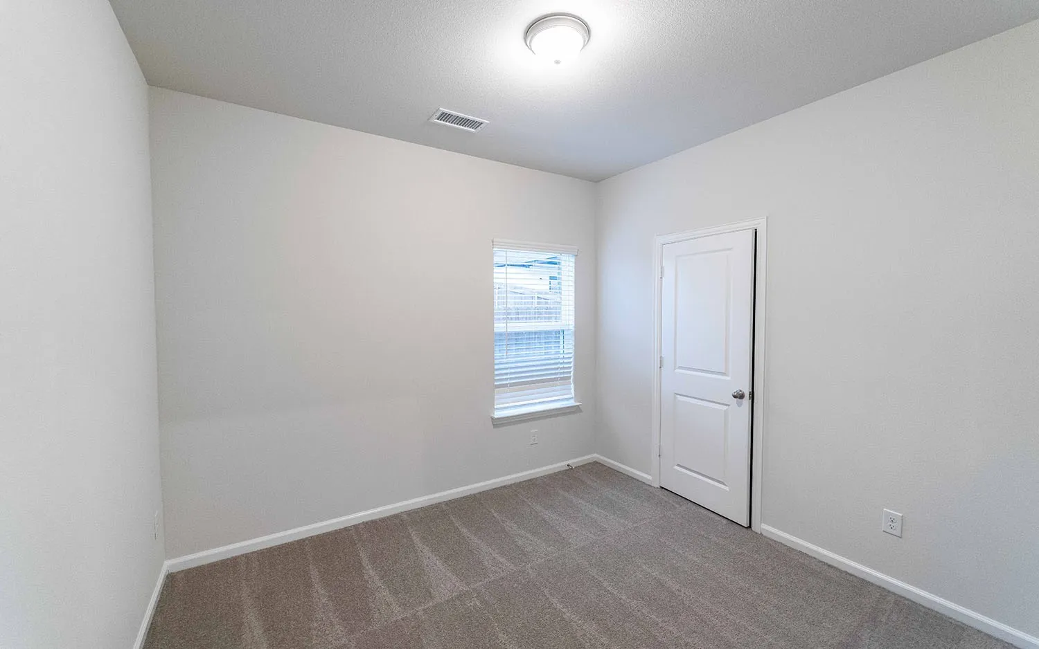 Neutral wall finishes with a window, white window blinds, and light gray patterned carpeting