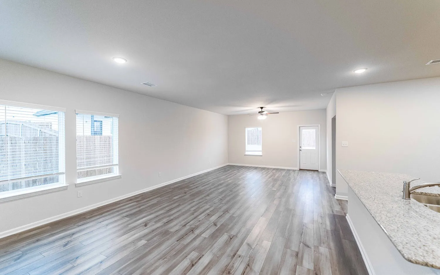 Spacious room featuring wood-finish flooring, recessed lighting, and bright white walls