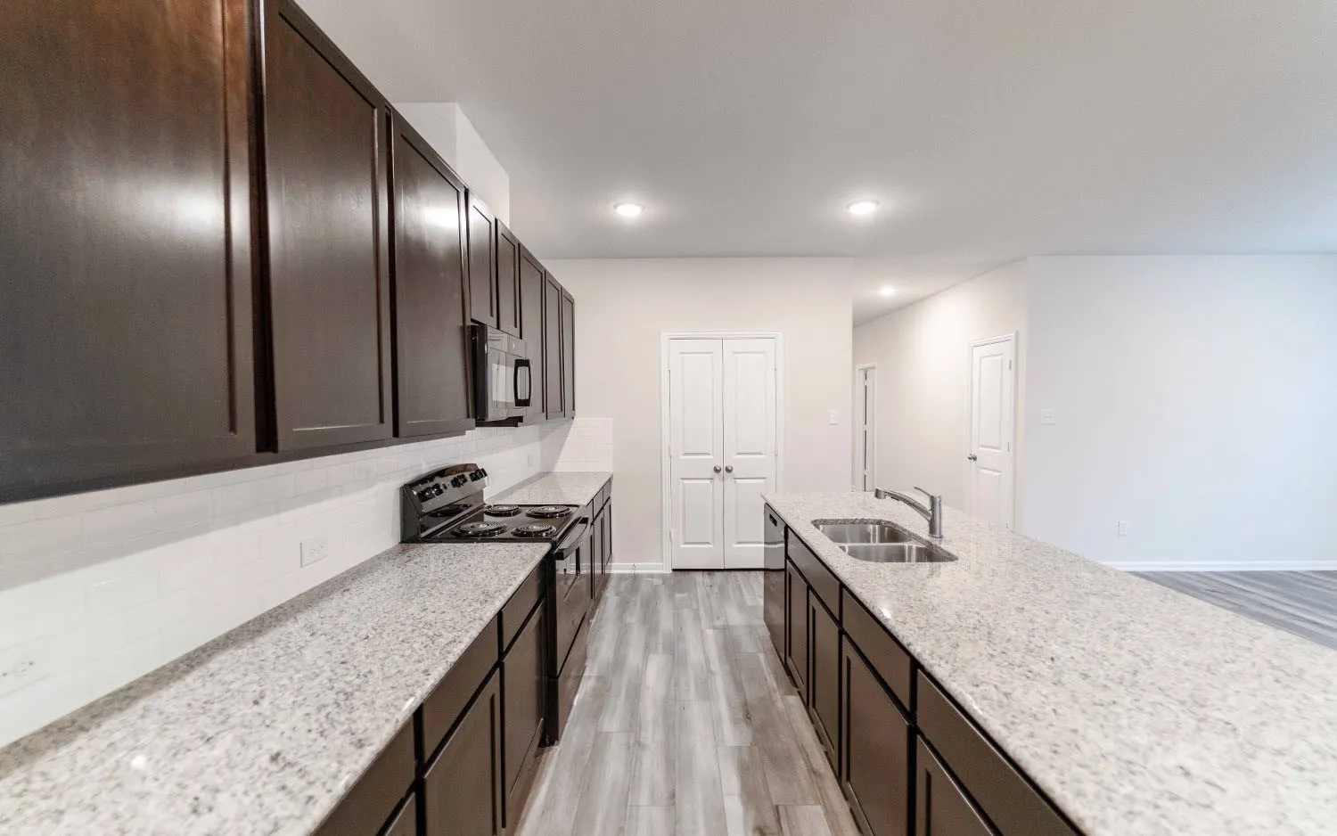 Kitchen featuring dark wood-finish cabinetry, light-toned countertops, and a white subway tile backsplash