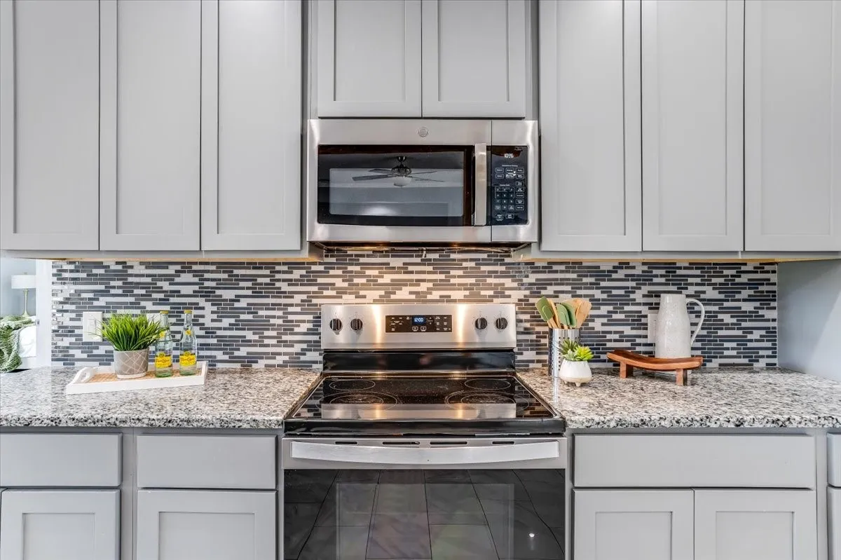 Modern kitchen featuring light gray shaker-style cabinetry, a stainless steel range, and an over-the-range microwave