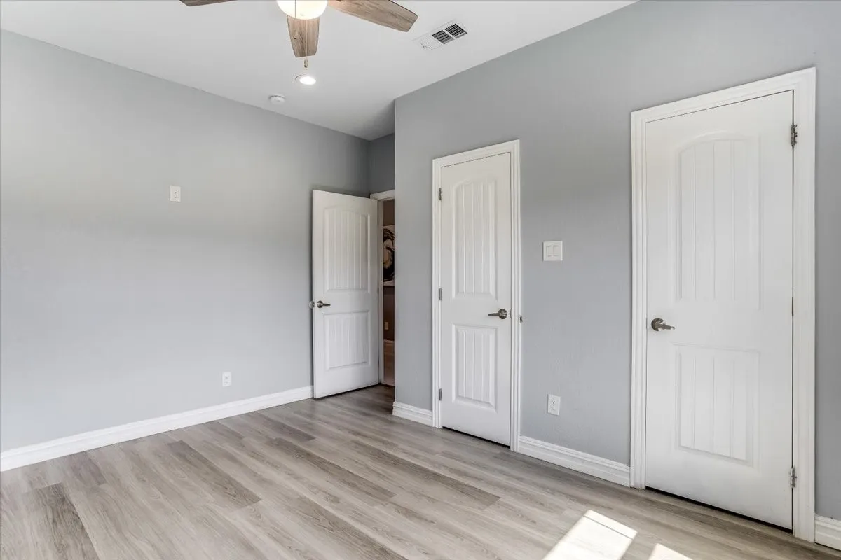 Spacious room featuring wood-finish flooring, light gray walls, and white baseboards
