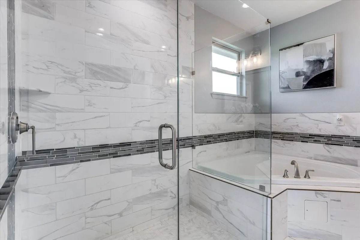 Spacious shower with clear glass enclosure, subway tile surround, mosaic accent band, and brushed nickel fixtures