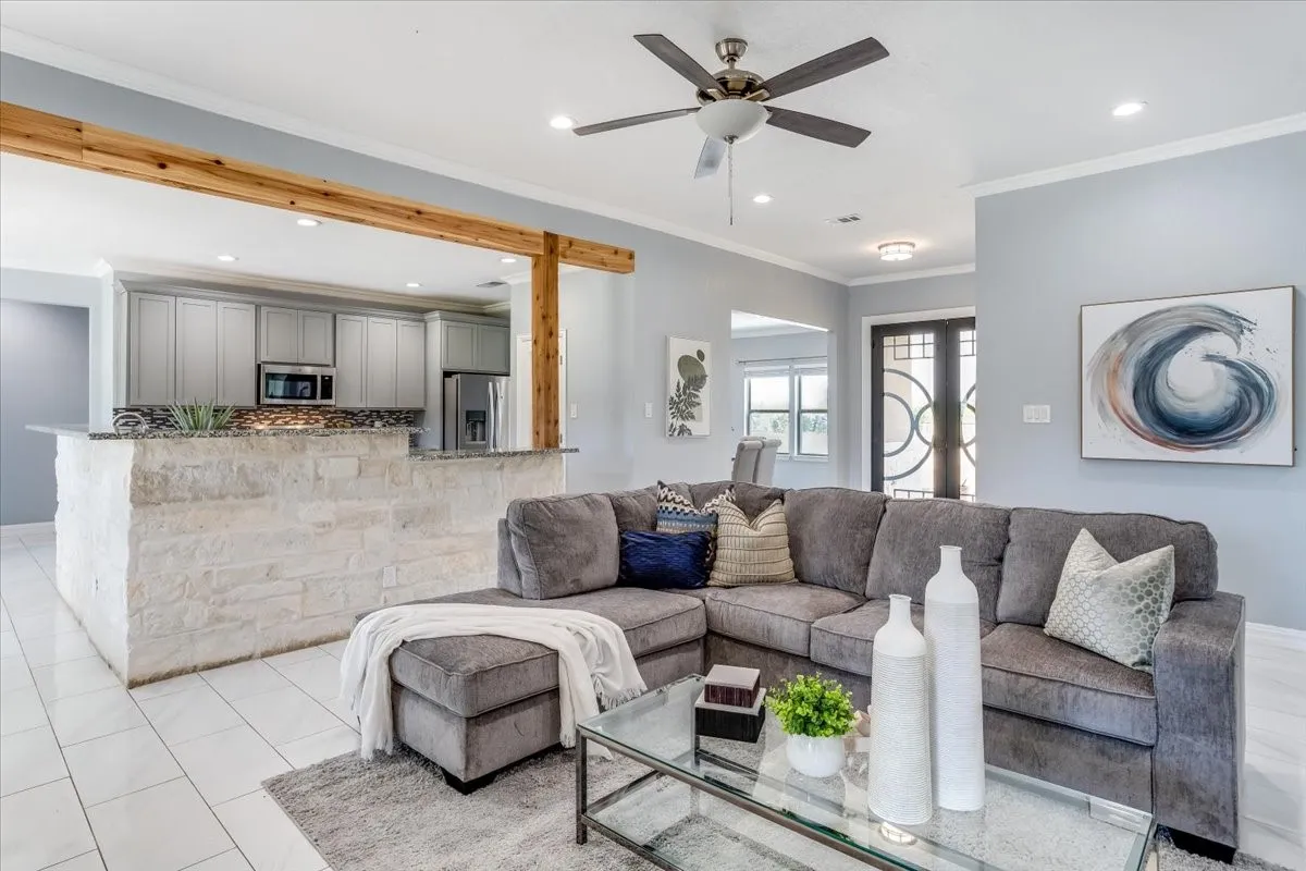 Living space featuring a stone-clad breakfast bar with a granite countertop, open to a kitchen with light gray cabinetry and stainless steel appliances