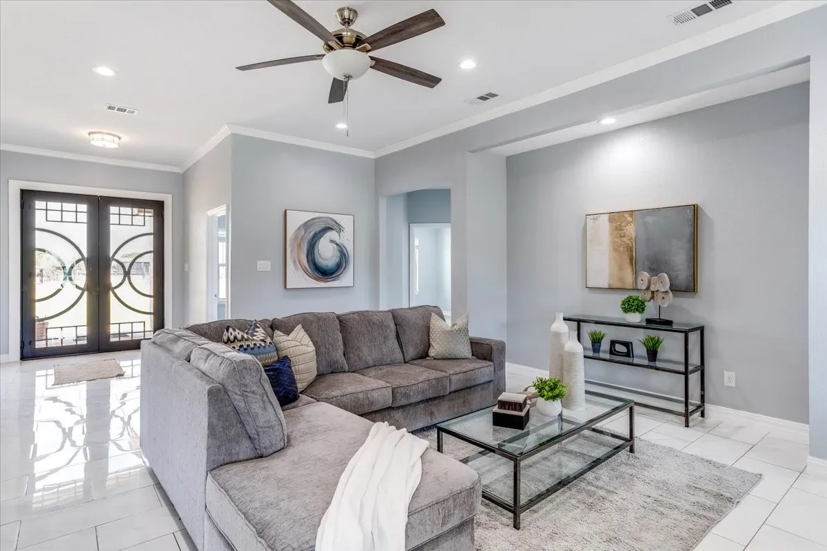 Spacious living area featuring polished tile flooring, recessed lighting, crown molding, and a ceiling fan