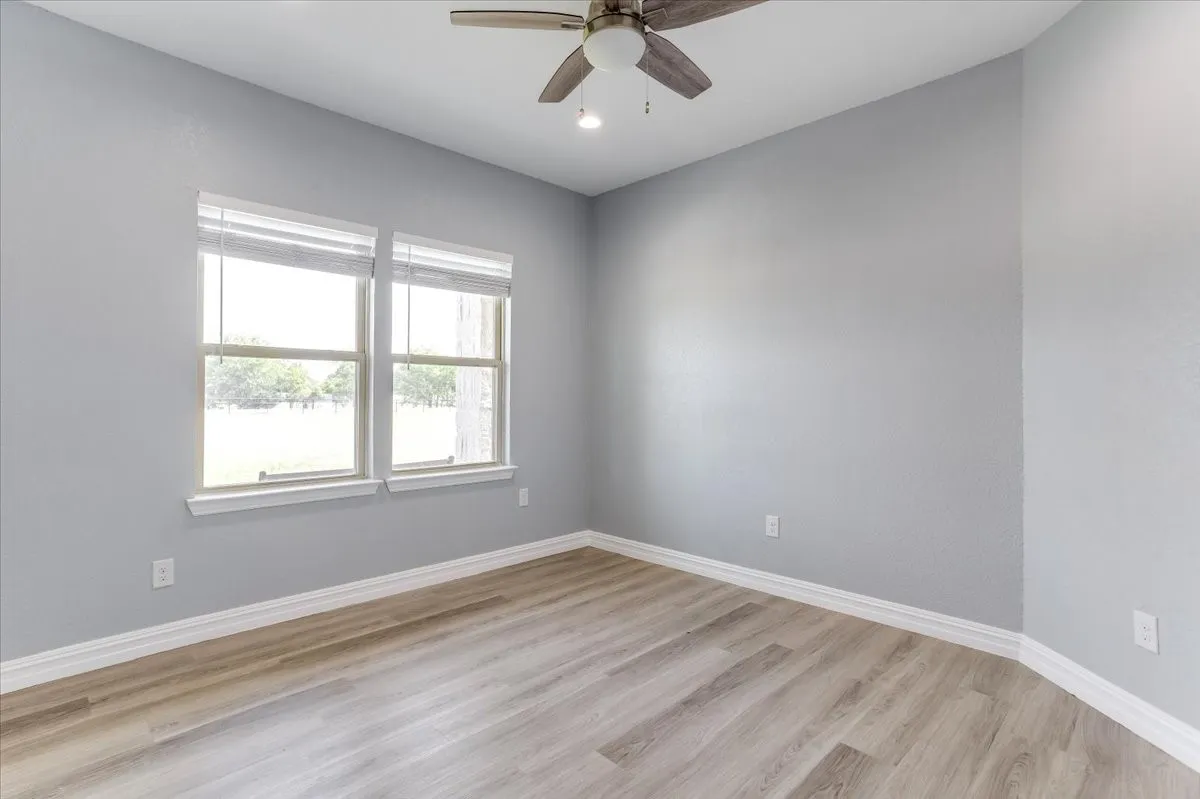 Room featuring wood-finish flooring, light grey walls, and white baseboards