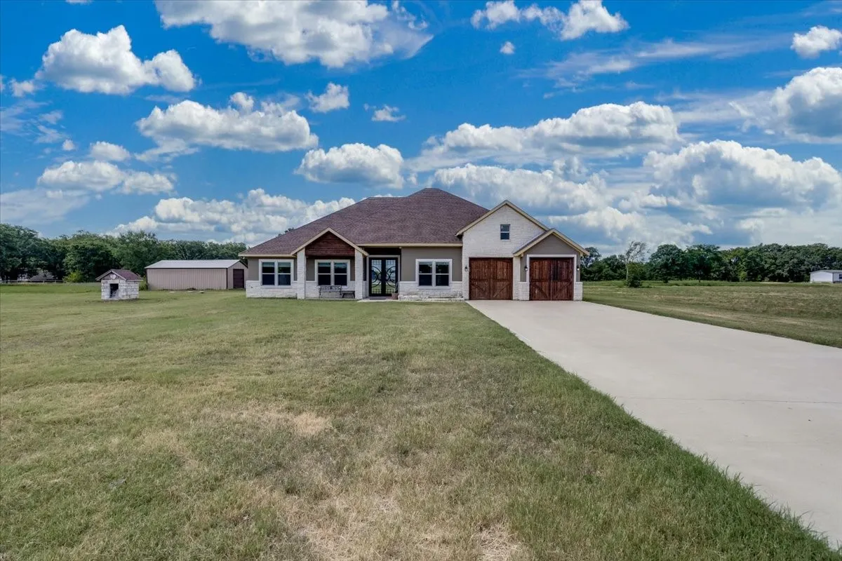 Contemporary ranch-style residence featuring a brown shingle roof, light-toned siding, and stone accents
