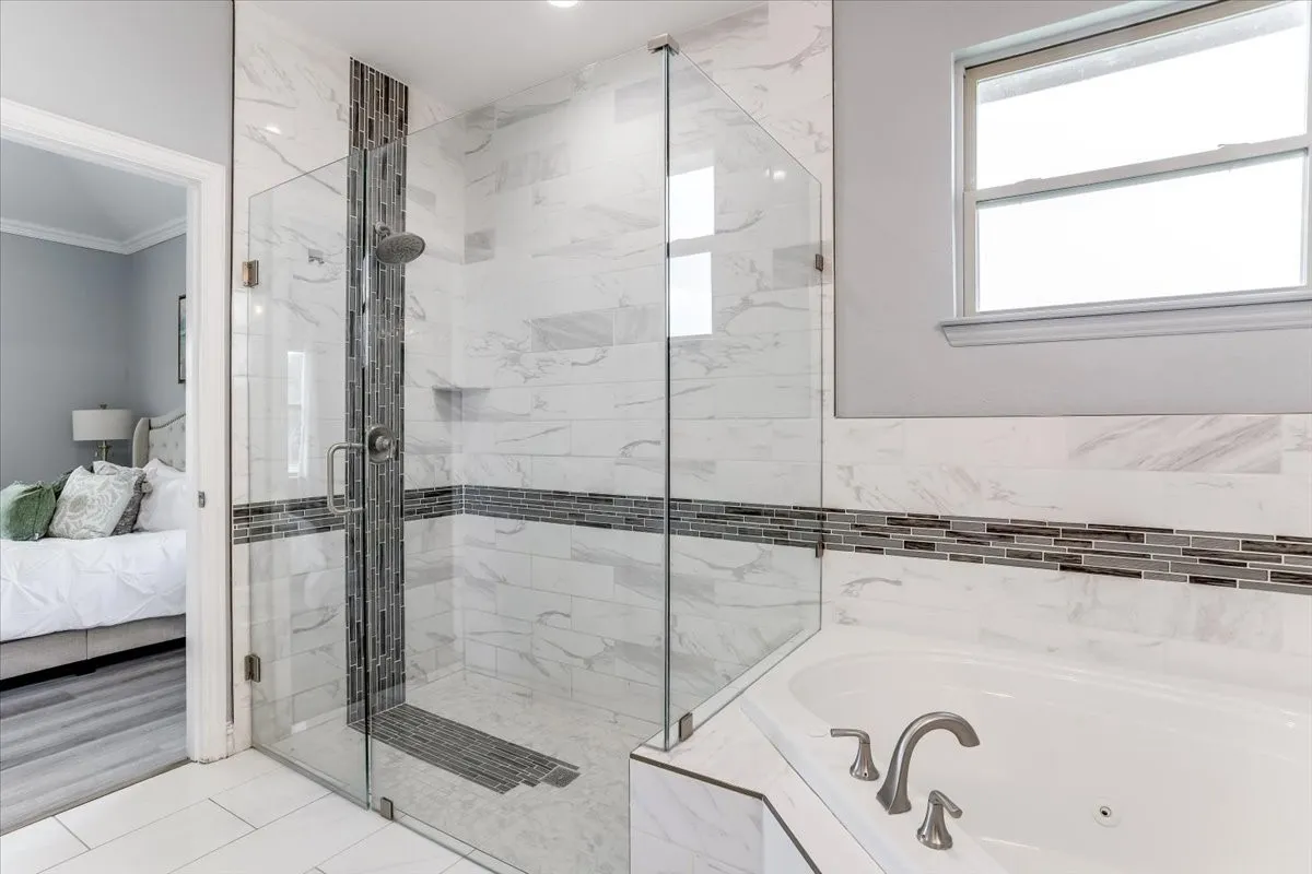 Glass-enclosed shower with subway tile surround and mosaic accent band