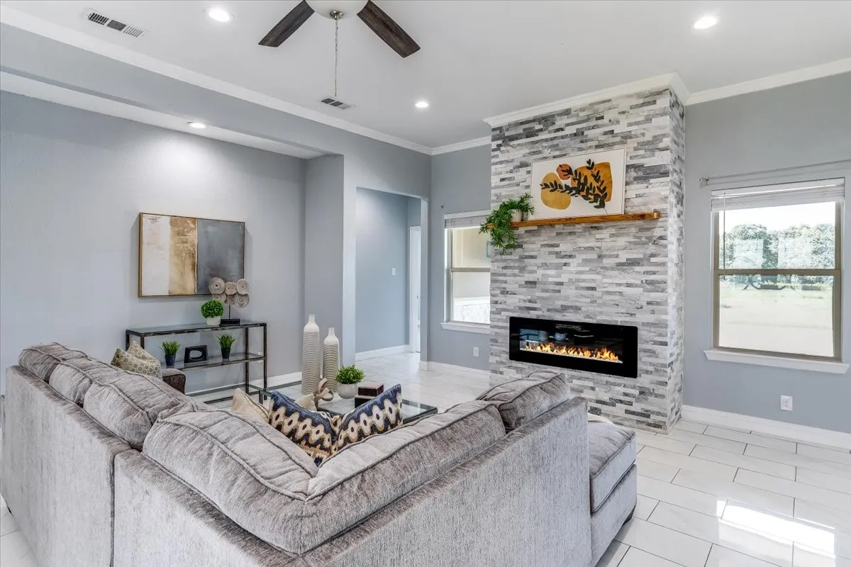 Living area featuring a floor-to-ceiling stone-look fireplace with a built-in electric insert, a wood mantel, and multiple windows