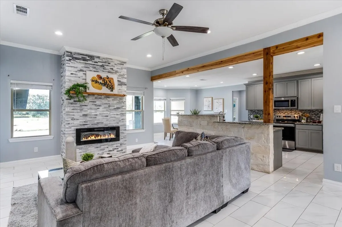 Living area featuring a floor-to-ceiling stacked stone fireplace with an electric insert and a wood mantel