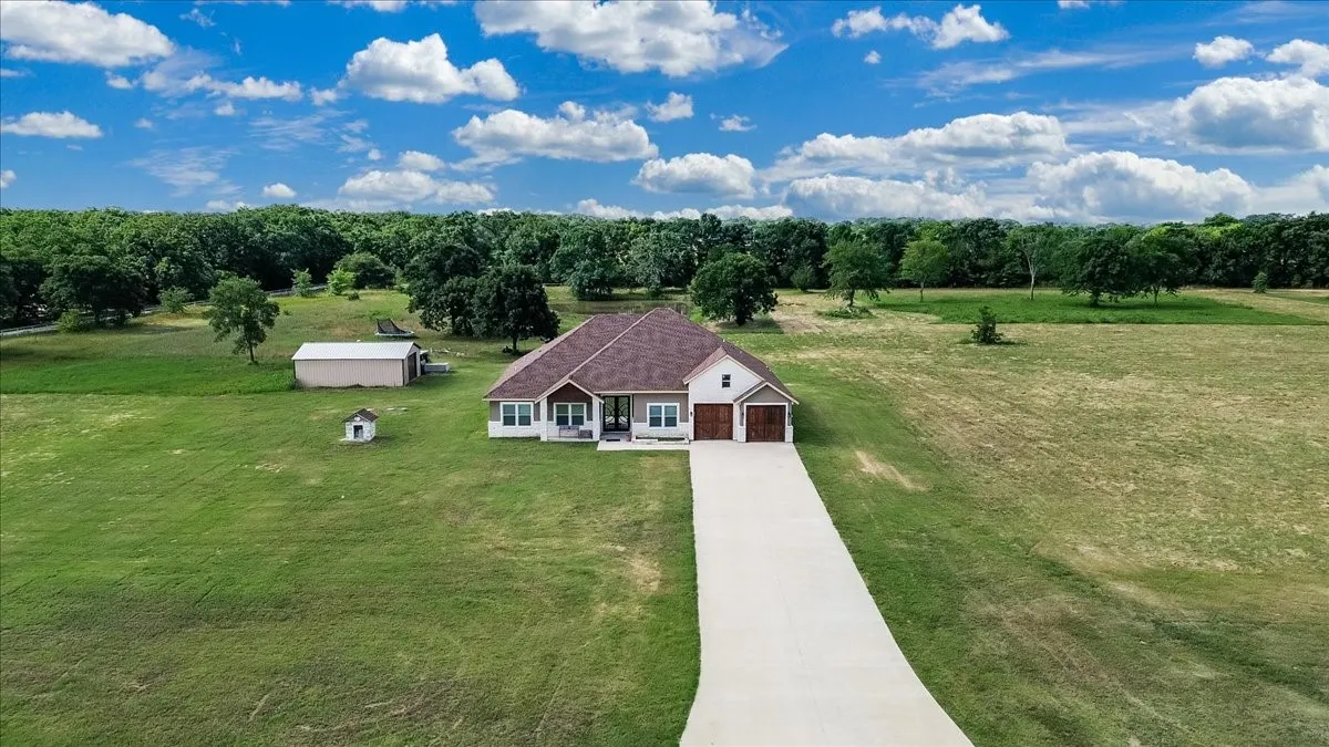 Ranch-style residence featuring a two-car garage, covered porch, and a gravel driveway