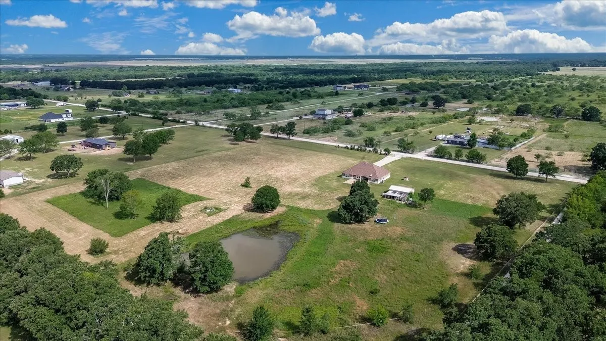 Expansive property featuring a private pond, mature trees, open fields, and a detached structure