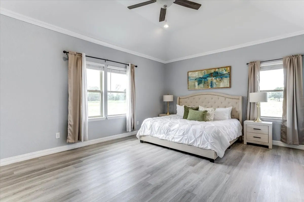 Spacious room featuring vaulted ceilings, wood-finish flooring, and multiple windows