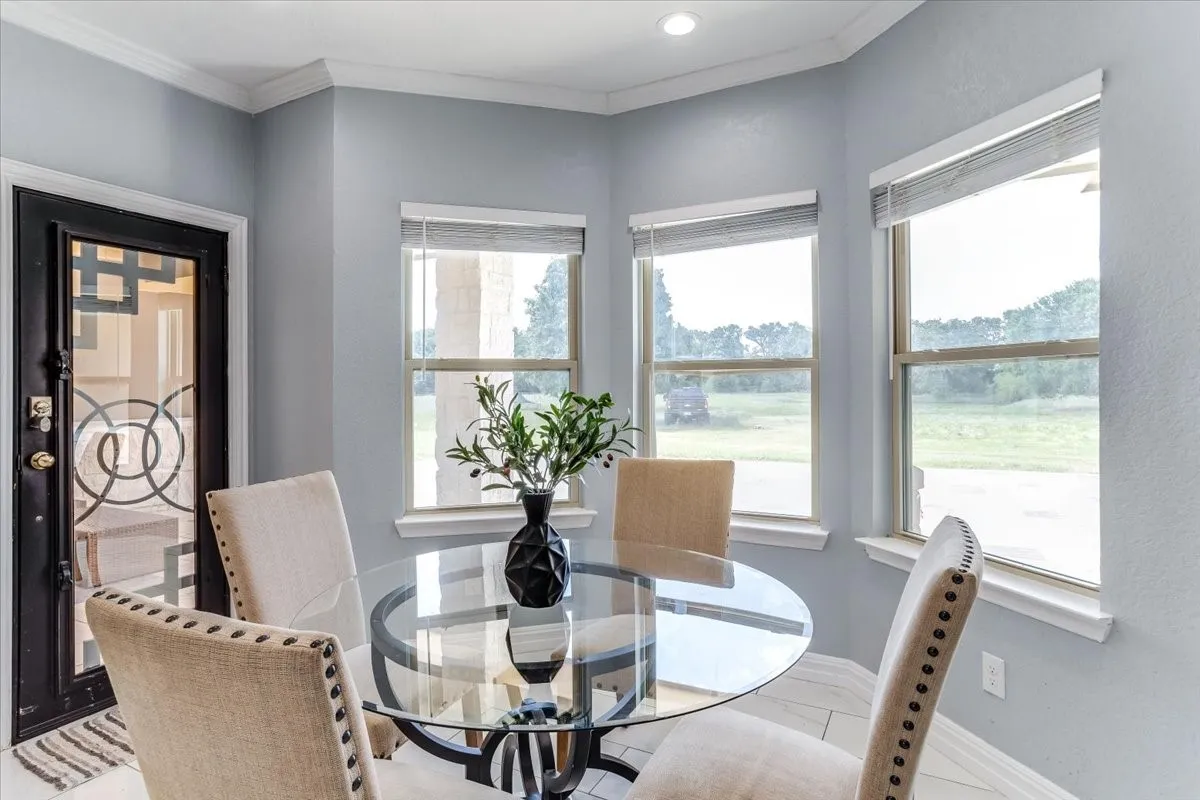 Corner dining area with three windows, recessed lighting, crown molding, and a decorative glass-paneled entry door