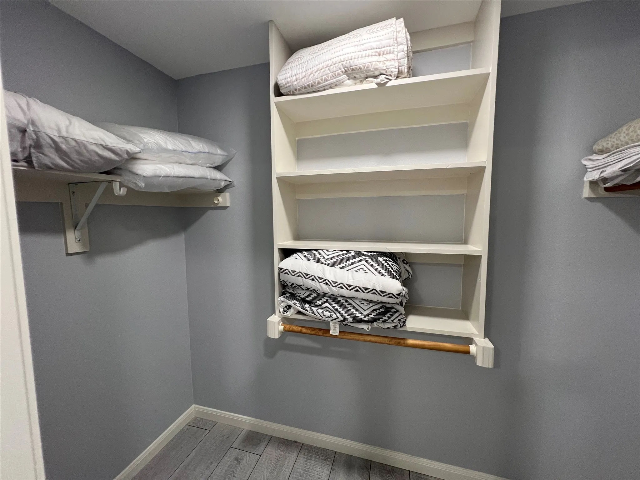Built-in shelving unit with multiple storage tiers and a hanging rod, complemented by additional wall-mounted shelving