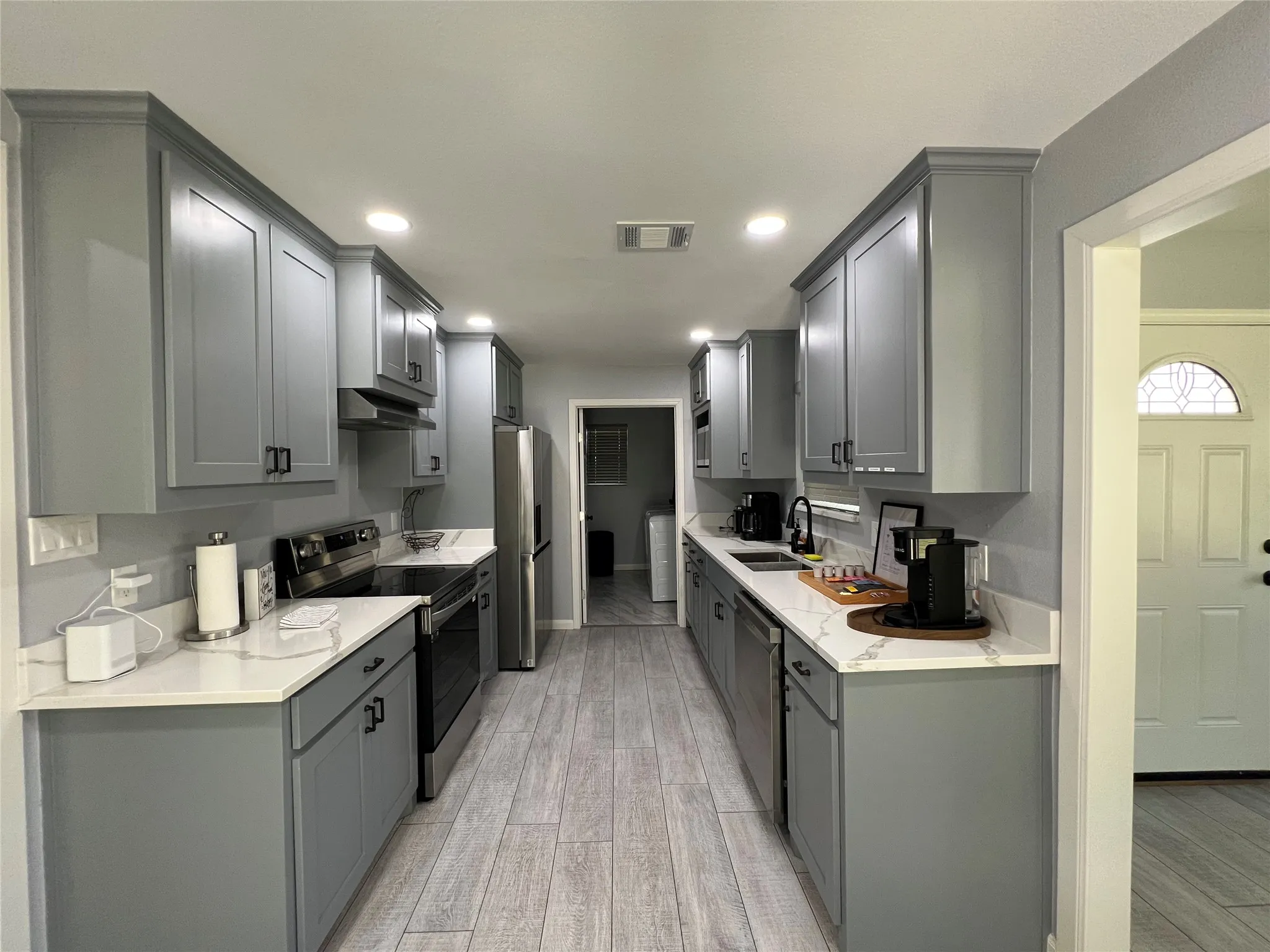 Galley kitchen featuring gray shaker-style cabinetry, white countertops, and wood-finish flooring