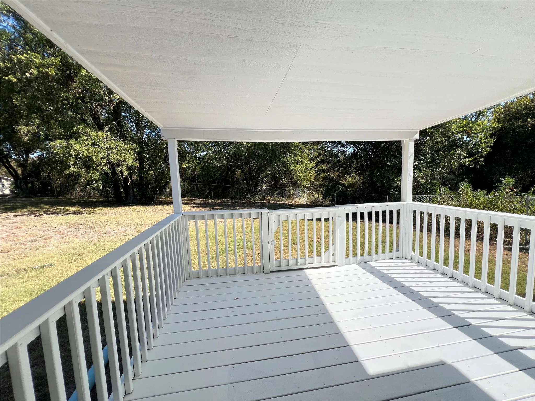 Covered outdoor deck with white painted wood flooring and railing