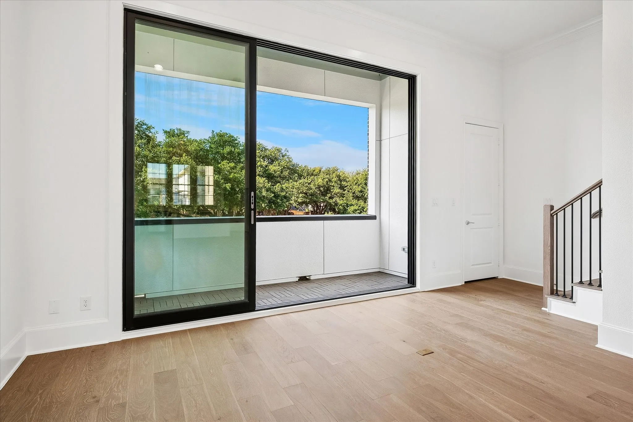 Sliding glass door opening to an outdoor balcony with a glass railing
