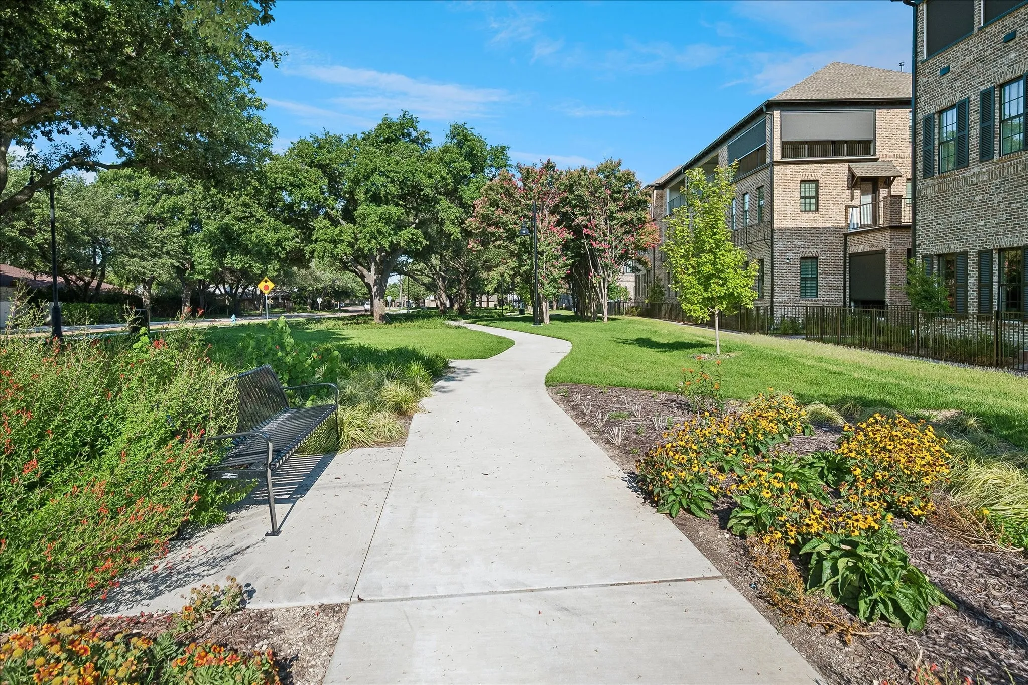 Curved concrete pathway with manicured lawn and mature trees
