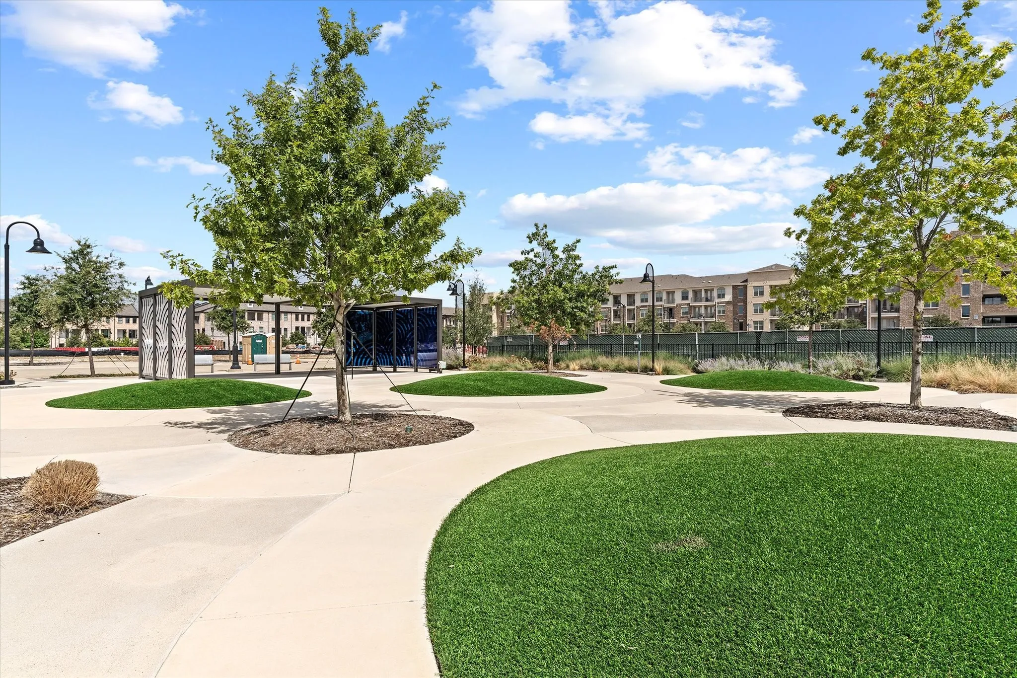 Expansive green space featuring artificial turf mounds and mature trees