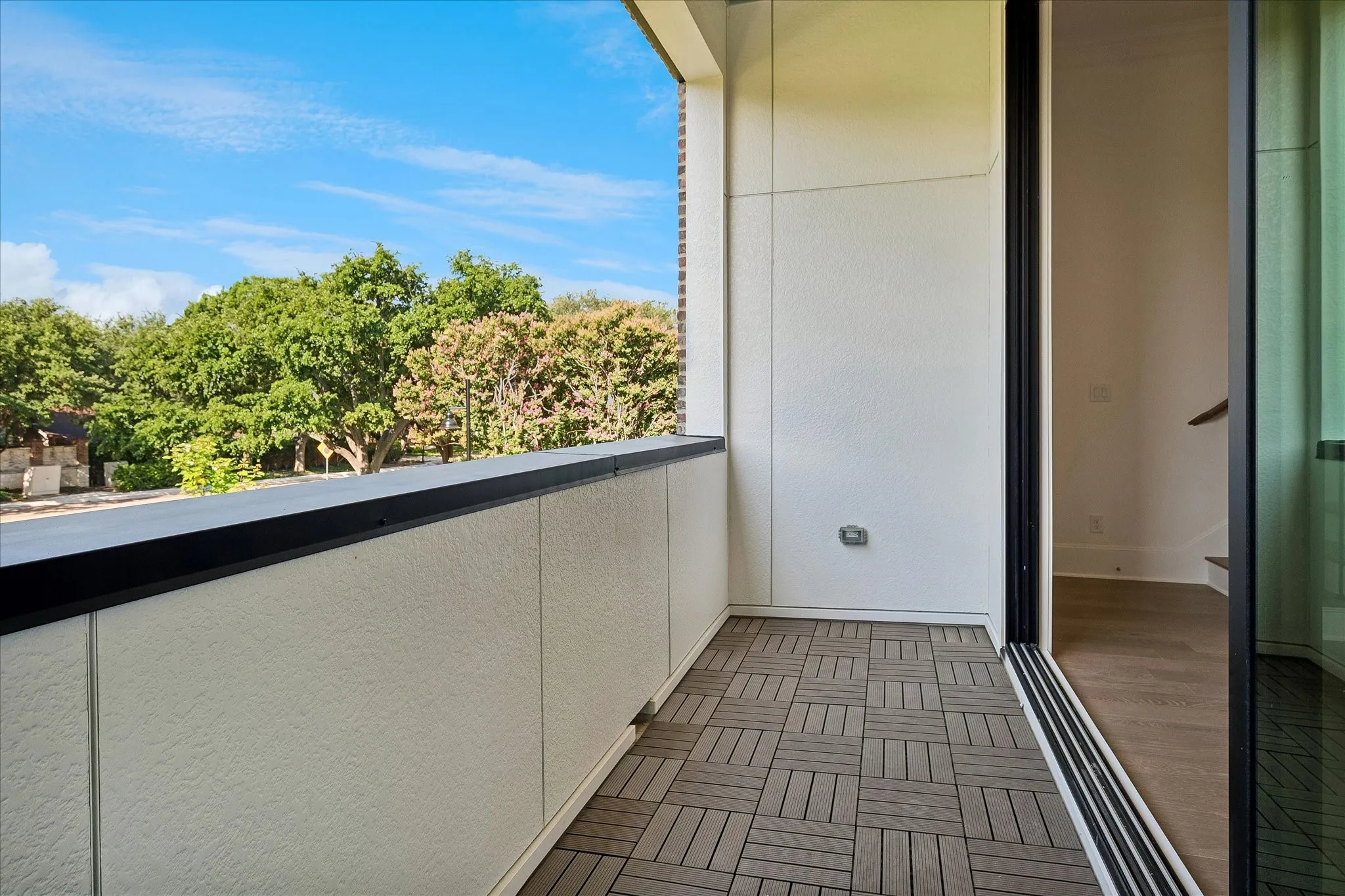 Outdoor balcony featuring modular wood-finish flooring and a black railing