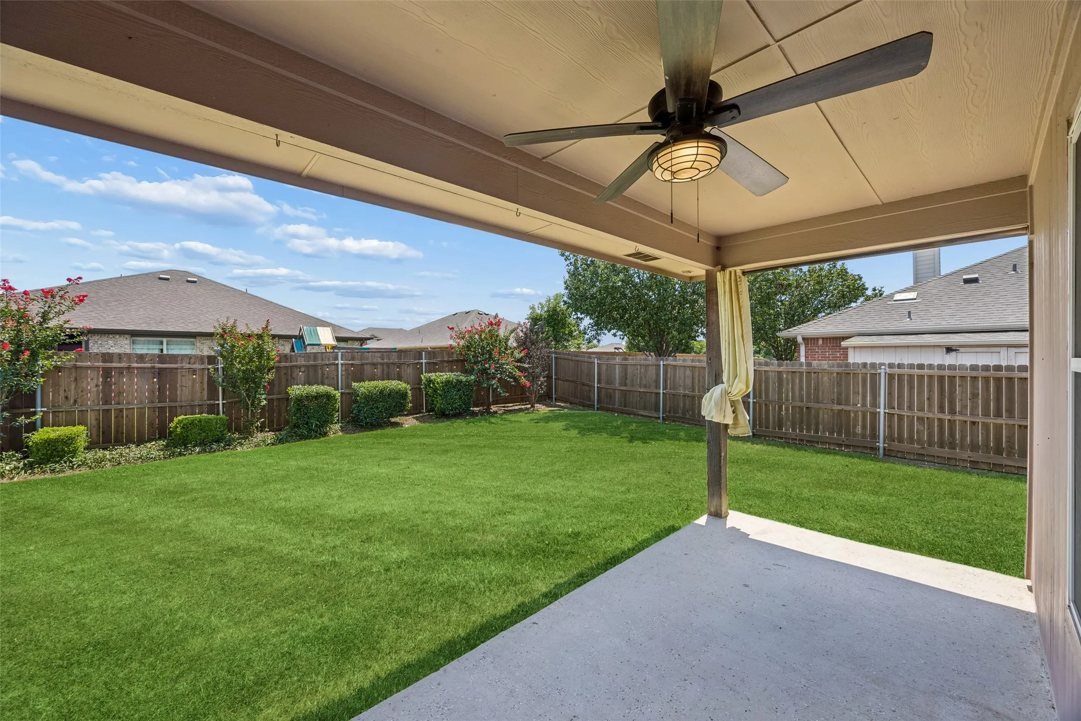 Your backyard retreat awaits with a covered patio, ceiling fan, and an expansive lawn that's perfect for entertaining, outdoor dining, or simply relaxing in the shade.