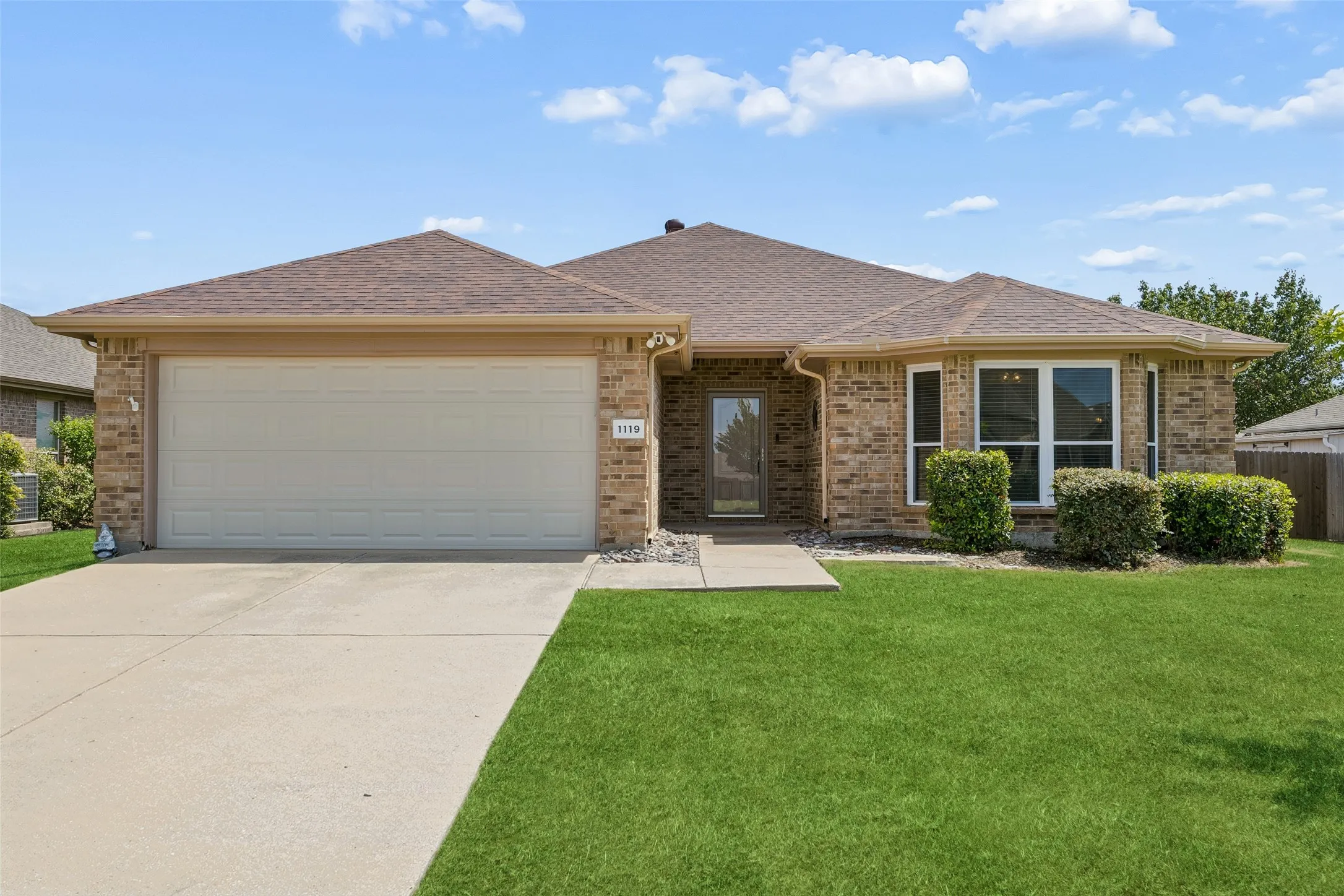 Warm and welcoming exterior showcases a well-maintained lawn, beautiful brick architecture, and a covered front entry at 1119 Wolverine Lane.
