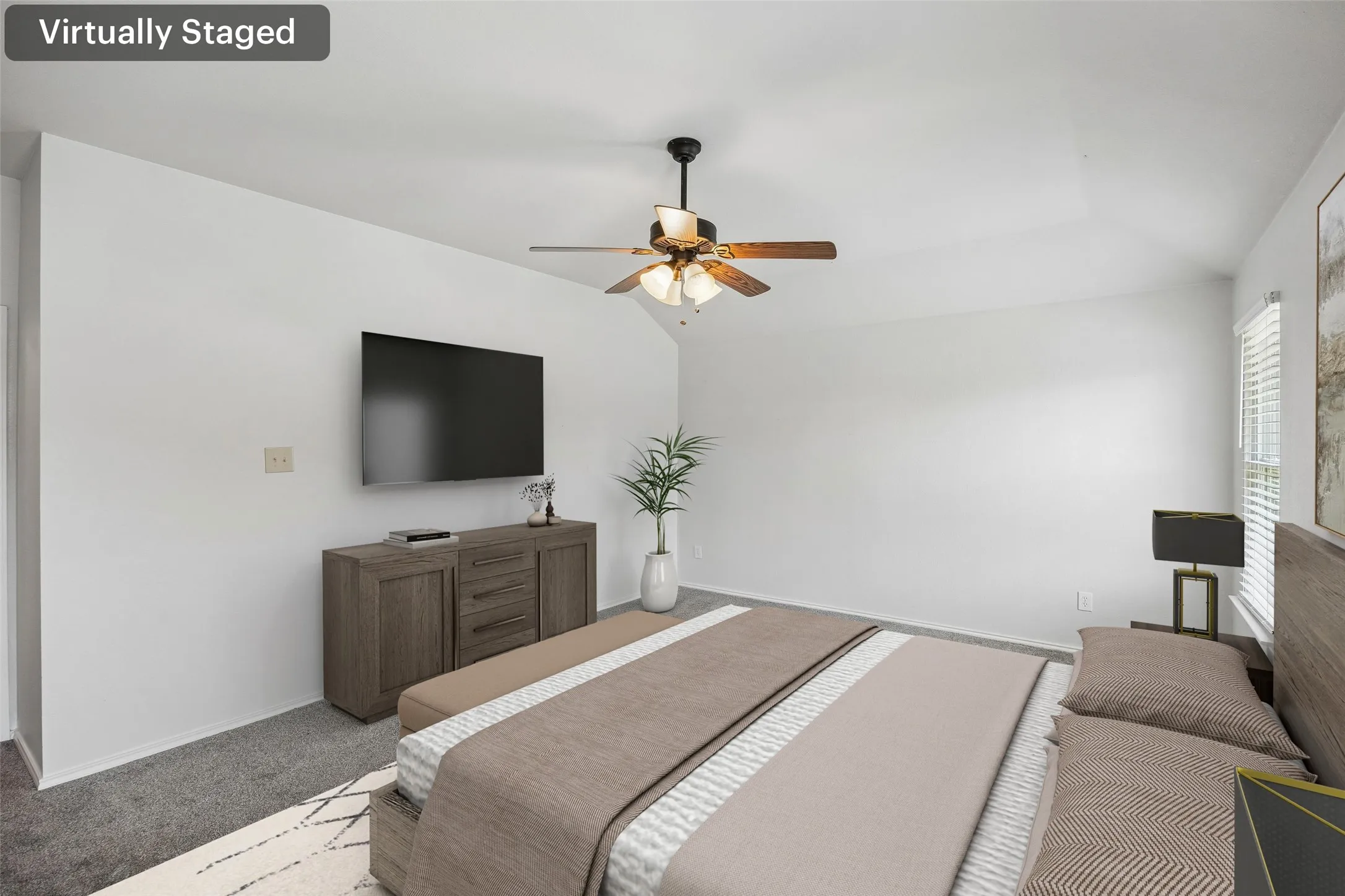 The expansive primary bedroom offers a bright, airy feel with neutral finishes, abundant natural light, and a ceiling fan. (Virtually staged.)