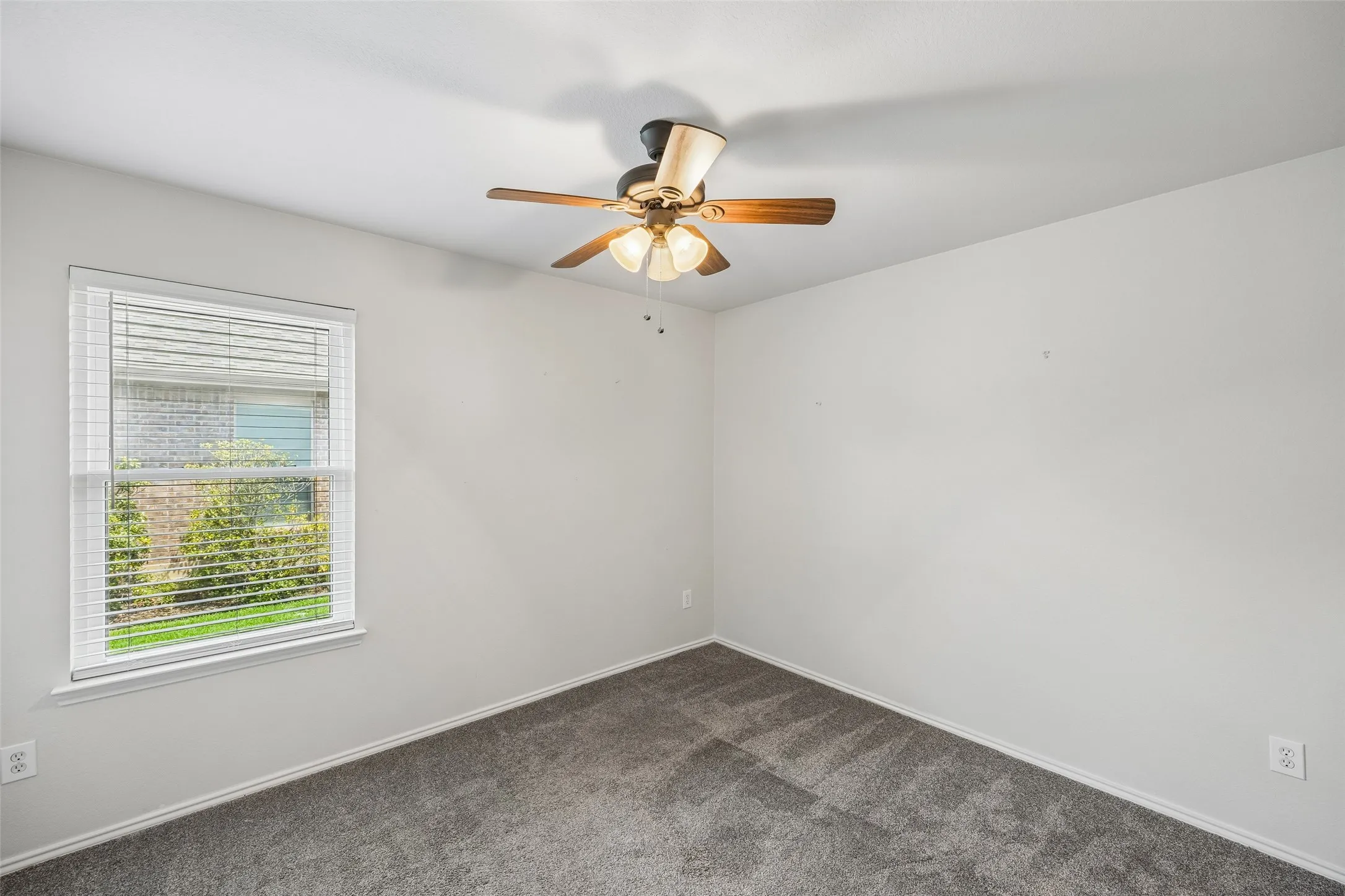 Designed with comfort in mind, this secondary bedroom offers a bright, airy feel with neutral finishes and a ceiling fan.