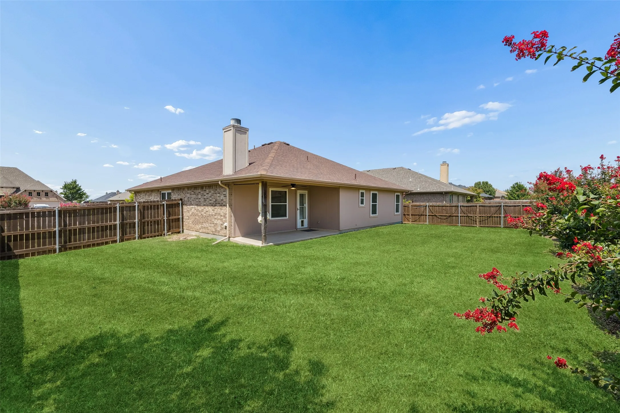 Enjoy a spacious, fully fenced backyard featuring lush landscaping, a covered patio, and plenty of room for outdoor entertaining, gardening, or recreation.