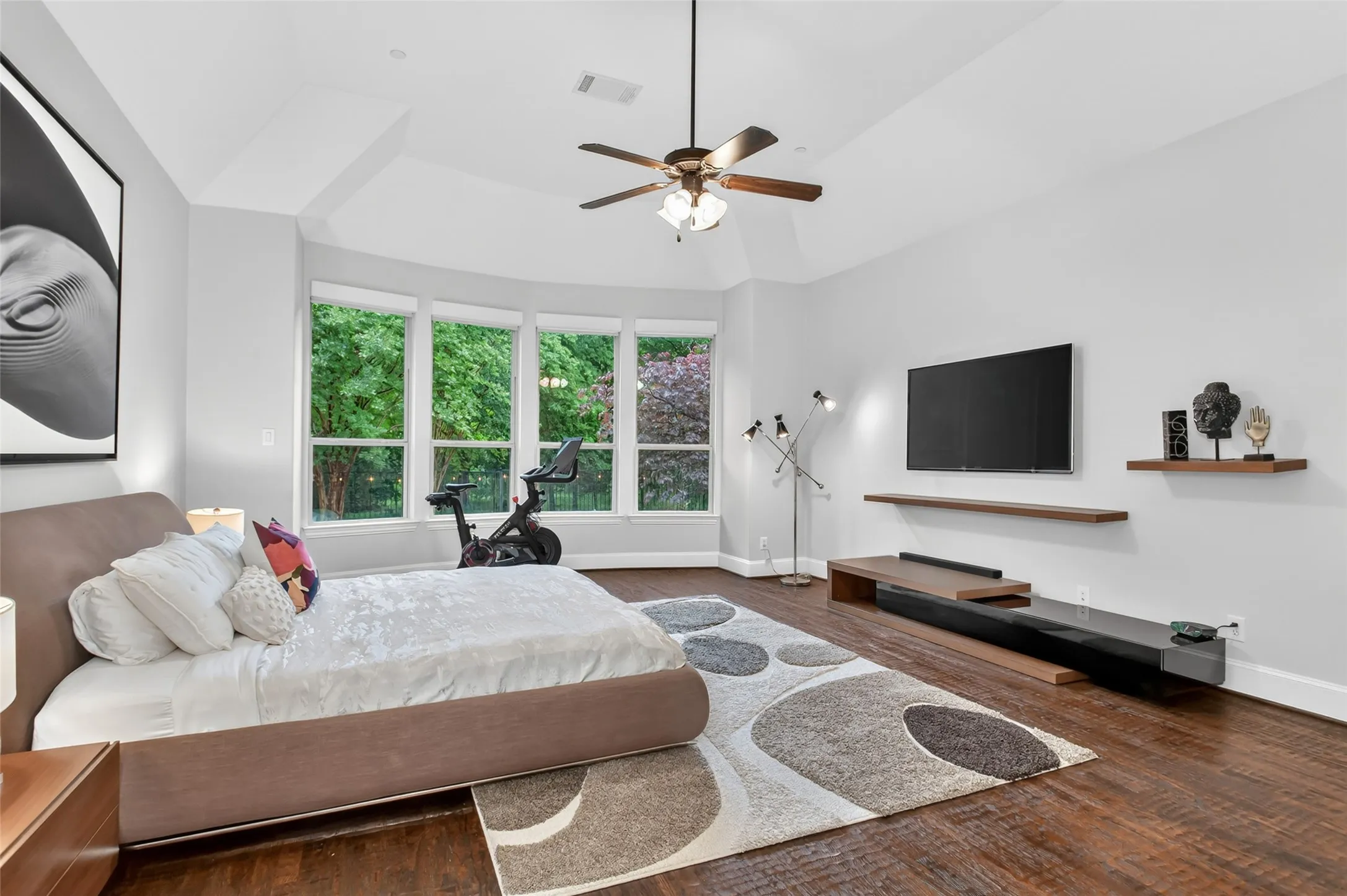 Tray ceiling with a ceiling fan, dark wood-finish flooring, and a bay window featuring multiple large panes