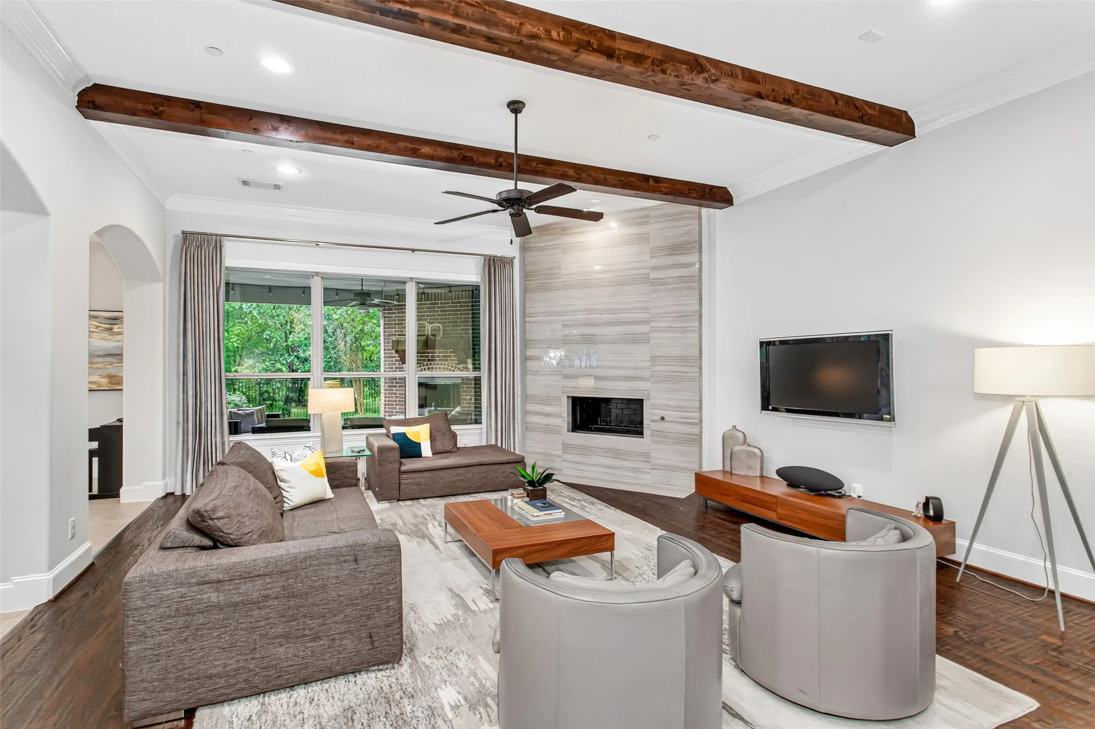 Living area featuring wood-finish flooring, exposed ceiling beams, and a modern fireplace with a tiled surround