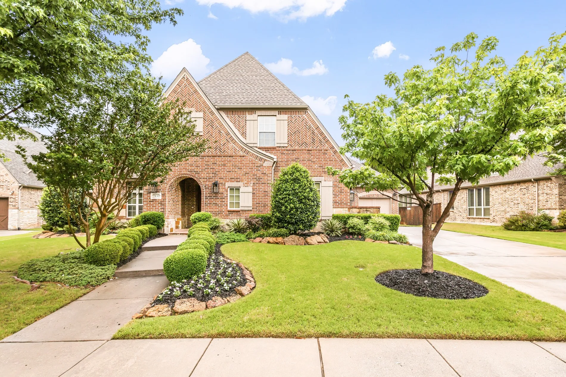 Brick exterior featuring a gabled roofline, arched entry, and decorative shutters