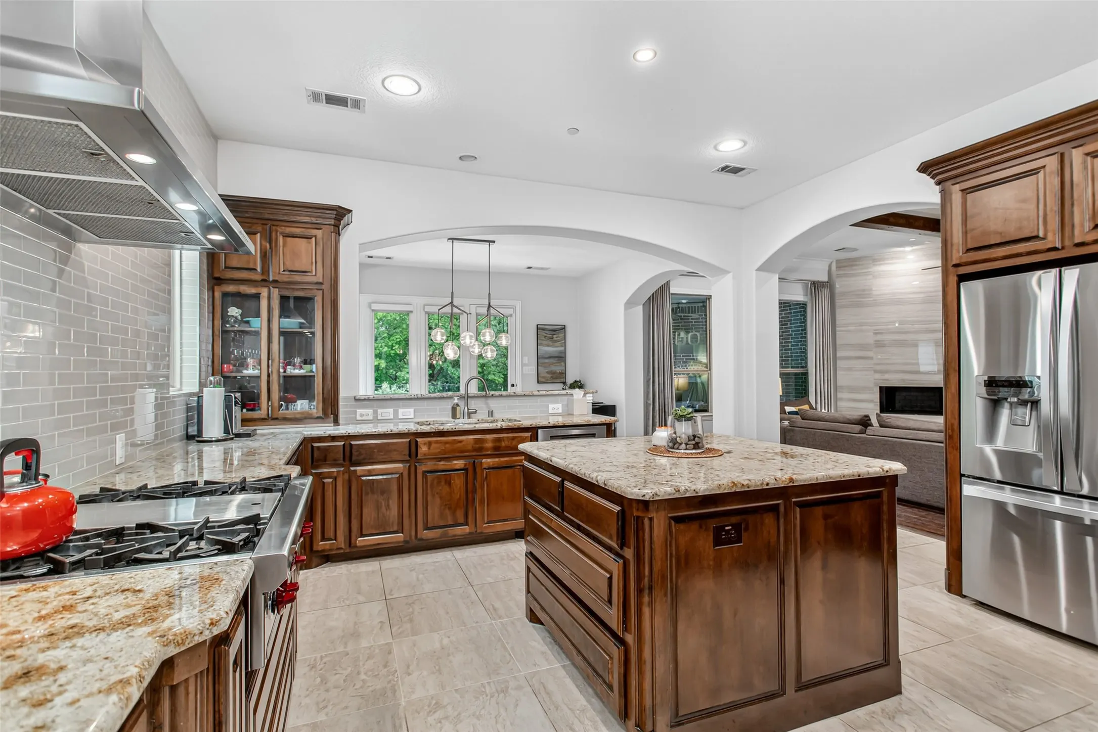 Gourmet kitchen featuring a granite island, stainless steel appliances, wood cabinetry, and tiled flooring