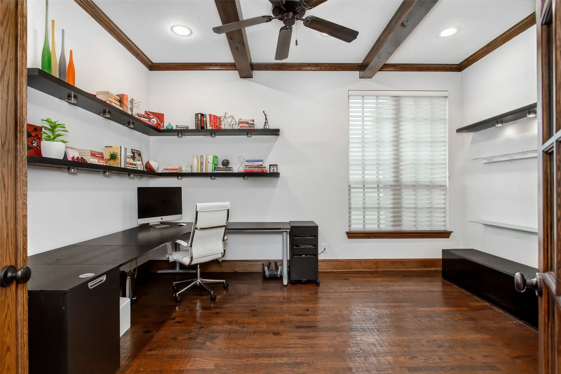Hardwood flooring in a room featuring exposed wood ceiling beams and a ceiling fan