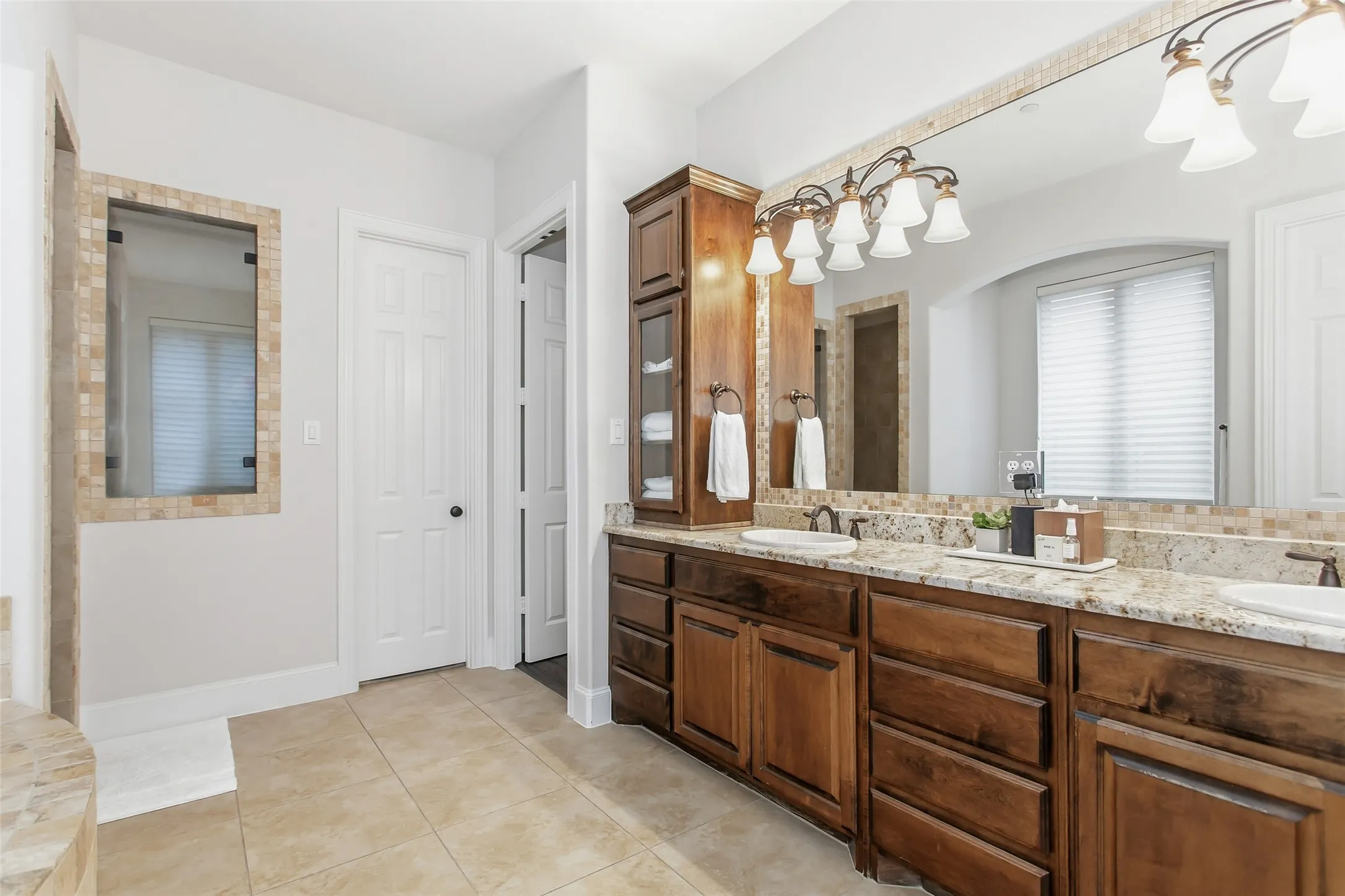 Dual vanity with wood cabinetry, light granite countertops, and two undermount sinks